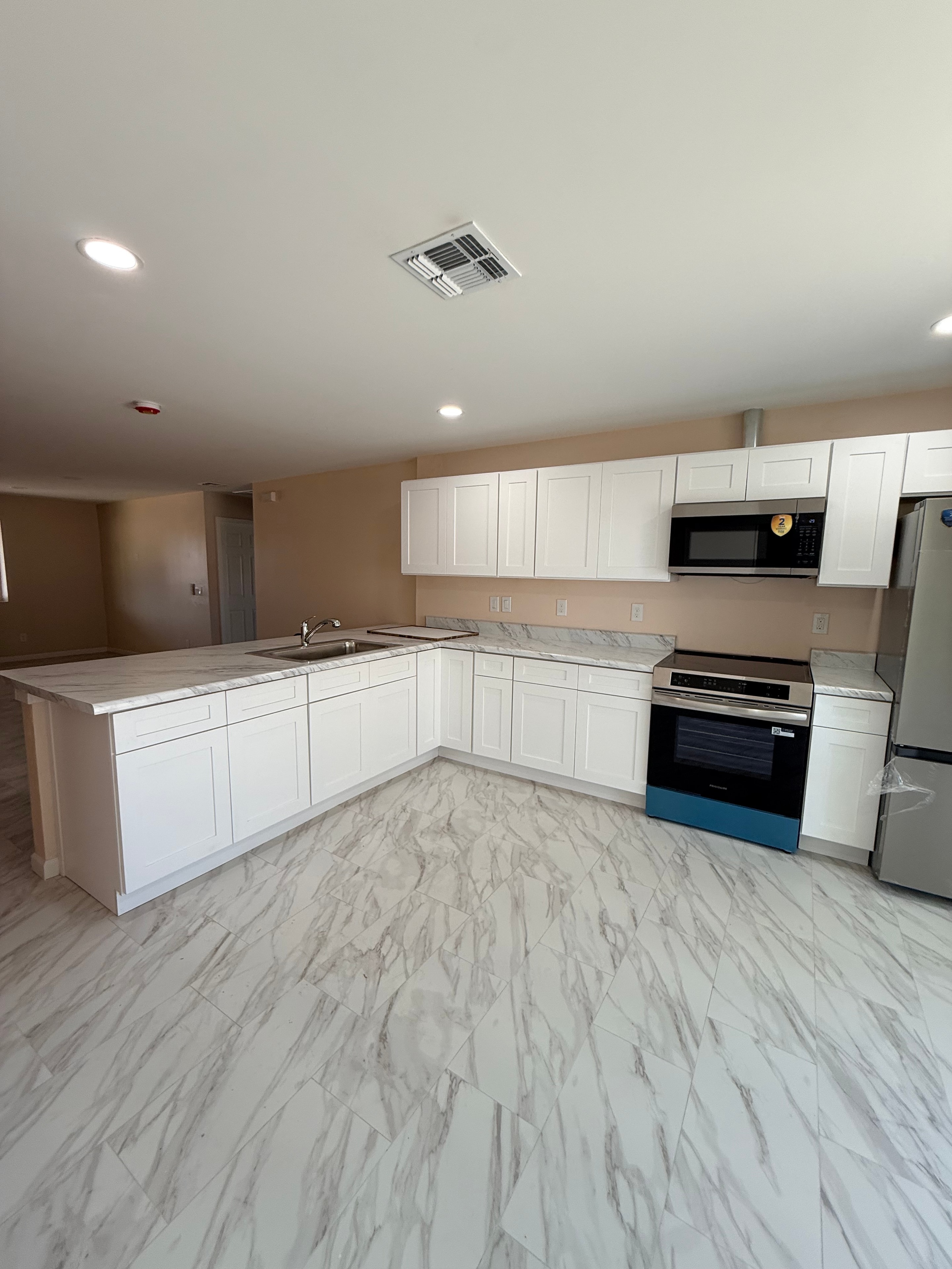 Renovated kitchen with white shaker cabinets and marble tile backsplash
