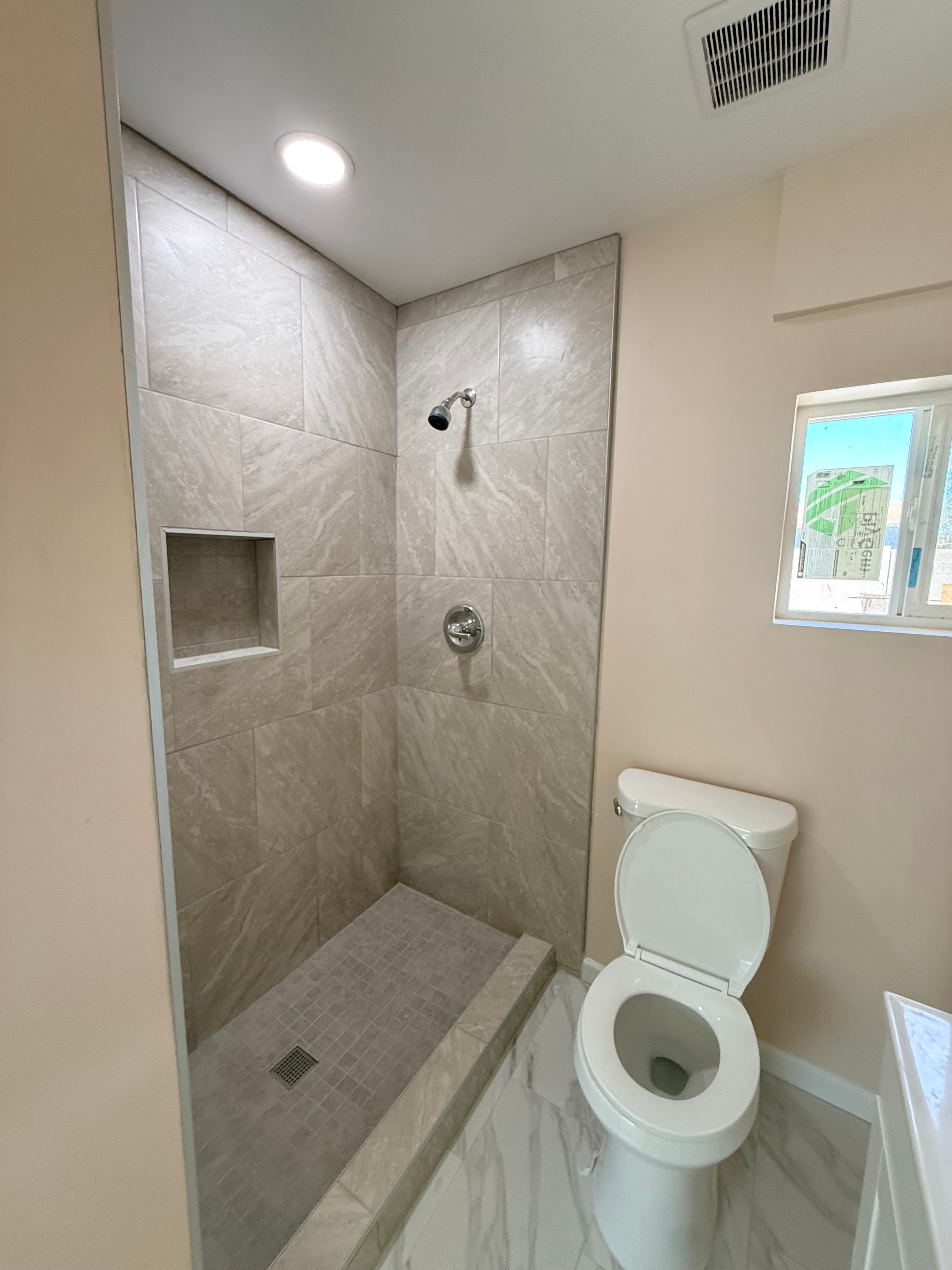 Completed bathroom with walk-in shower and marble tile surround